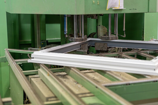 Vue de cadres menuiseries aluminium de vitres blancs dispos&eacute;s en atelier, illustrant un environnement de fabrication ou de pr&eacute;paration de menuiseries avec un aspect industriel et organis&eacute;.