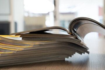Close up of stacked open magazines showing curved pages and blurred background. Publishing, journalism and printed media concept with room for text.