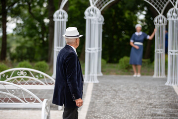 Obraz premium Couple reuniting at a garden arch during a sunny day in a tranquil park setting in summer