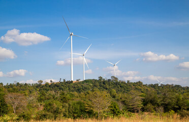 Wind turbines farm on green mountain range under blue sky, Renewable energy concept.