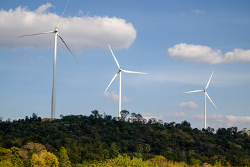 Wind turbines farm on green mountain range under blue sky, Renewable energy concept.