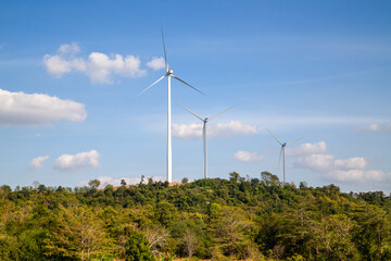 Wind turbines farm on green mountain range under blue sky, Renewable energy concept.