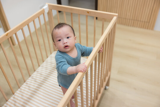 Little baby standing inside crib at home