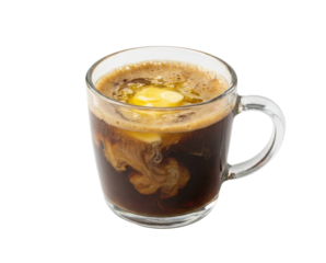 A glass cup filled with dark coffee and a raw egg, showcasing swirling patterns of creaminess.