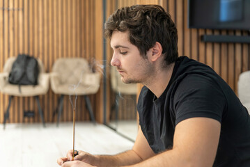White man with smoking incense stick in room
