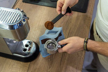 Black plastic scoop with ground coffee over portafilter