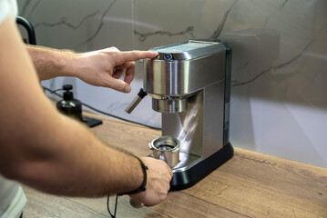 Man pressing button on steel espresso machine