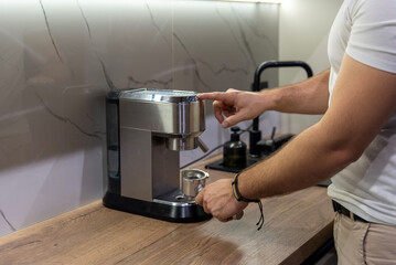 Man pressing button on steel espresso machine with portafilter