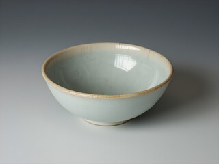 A white bowl with a brown rim sits on a white table