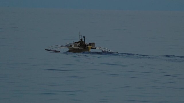 Solitary outrigger boat gliding across calm waters: serene seascape