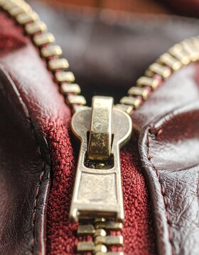 Close-up on a brassy zipper against a dark red textured fabric