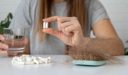 Woman holding vitamin capsules and a glass of water. Hair loss treatment concept