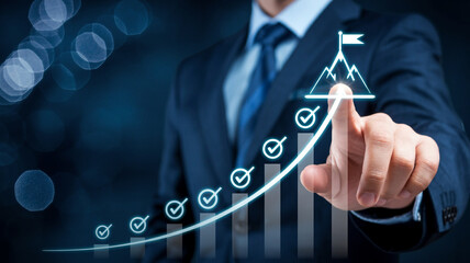 Businessman's hand interacts with glowing digital graph depicting business growth, progress, and goal achievement towards a mountain peak with a flag.