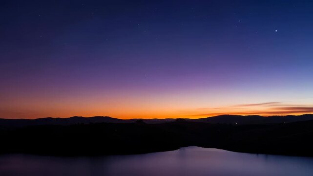 As dusk settles, an ethereal panorama unfolds, where the vibrant gradient hues of the sky dance with the silhouette of the mountain and lake. Witness the serene beauty.