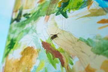 A close-up of a wasp on a canvas with vibrant abstract paint strokes, showcasing vivid greens and yellows.