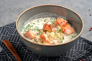 Creamy salmon soup with tender grilled salmon chunks, diced potatoes and fresh dill garnish in rustic bowl. Comforting Finnish-style fish chowder, healthy gourmet lunch or dinner dish.