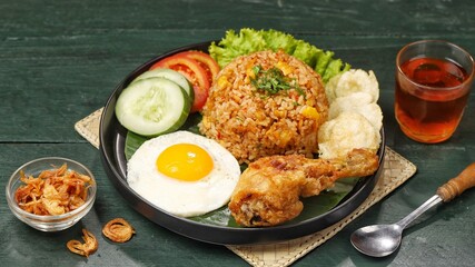 Nasi goreng. Fried rice with fried egg and fried thighs side dishes with sliced ​​cucumber and...