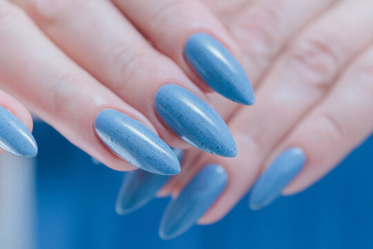 Woman's beautiful hand with long nails and light baby blue manicure	