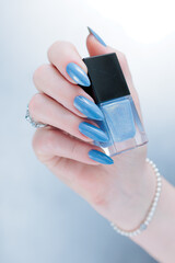 Fototapeta premium Woman's beautiful hand with long nails and light baby blue manicure 