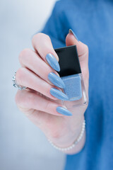 Fototapeta premium Woman's beautiful hand with long nails and light blue manicure