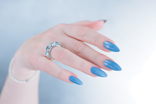 Woman's beautiful hand with long nails and light baby blue manicure	