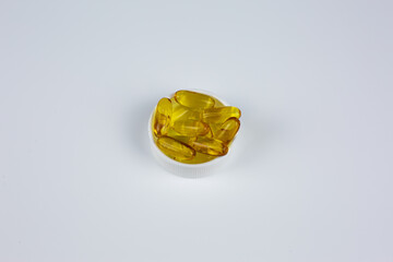 Golden fish oil capsules on white background. Omega-3 capsules for boosting immunity and overall health. Dietary supplement concept. Omega 3 capsules on white background