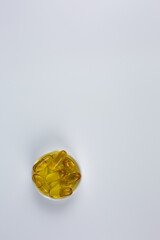 Golden fish oil capsules on white background. Vertical photo of Omega-3 fish oil capsules with space for text. Versatile dietary supplement for topics on medicine, health, and wellness