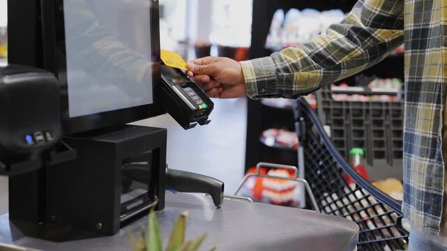 Young man wear casual clothes shopping at supermarket store grocery shop buy at self-service cash register use bank payment terminal to process acquire credit card. Purchasing food gastronomy concept