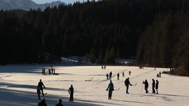 Lake Grubsee, Garmisch-Partenkirchen district, Upper Bavaria, Germany. Skating and playing hockey on natural ice of Grubsee, Bavaria. Sunny winter day, active recreation in the heart of German Alps