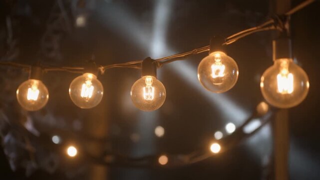 String of illuminated Edison-style light bulbs in the dark with bokeh lightbulb string lights