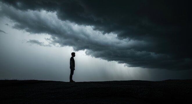 Silhouette of a person under a dark, stormy sky with ominous clouds