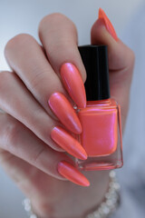 Female beautiful hand with long nails and a bright orange nail polish