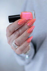 Female beautiful hand with long nails and a bright orange nail polish