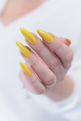 Female hand with long nails and a bottle of bright yellow neon nail polish