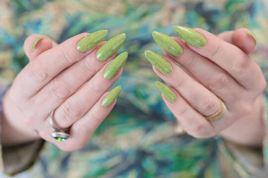 Female hand with long nails and yellow green manicure
