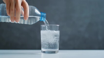 Person Pouring Water into Glass on White Surface