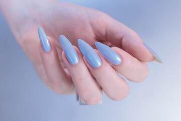 Fototapeta premium Woman's beautiful hand with long nails and light baby blue manicure