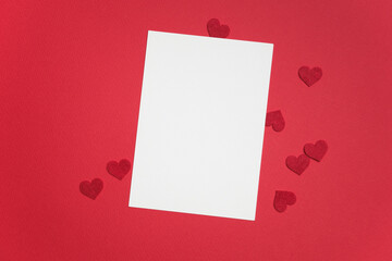 Blank greeting card mockup on vibrant red background with scattered red heart shapes, perfect for Valentine's Day design projects and romantic messages © nikavera