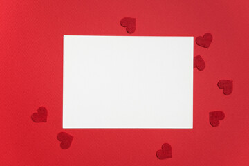 Blank greeting card mockup on red background surrounded by small red heart shapes, perfect for Valentine's Day design projects and romantic messages with copy space © nikavera