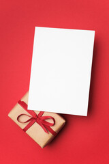 Blank greeting card mockup with copy space on vibrant red background, accompanied by a beautifully...