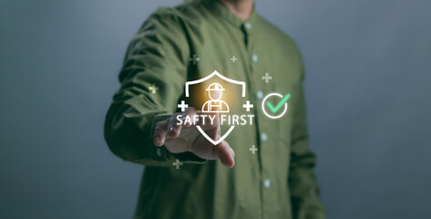 concept of safety first.man's hand touching a protective shield and worker symbol, represents workplace safety, industrial protection, risk management and health compliance