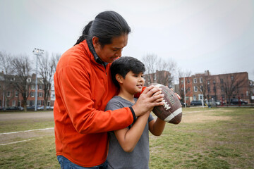 Philadelphia, Pennsylvania, USA. Native American father teaching his young son how to throw a football