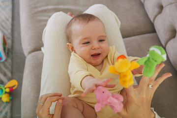 Mom entertains her baby with finger toys.