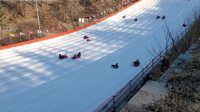 People Sledding Down a Snowy Slope on Tubes at a Winter Sledding Hill in Korea