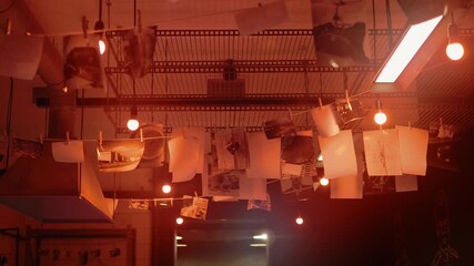 A large old-fashioned industrial photo lab with drying photographs, with baths for developing and fixing the image on photographic paper, with chemicals and other photographic equipment and, of course