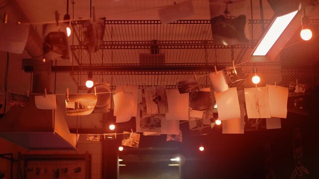 A large old-fashioned industrial photo lab with drying photographs, with baths for developing and fixing the image on photographic paper, with chemicals and other photographic equipment and, of course