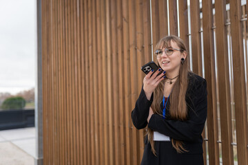 Businesswoman recording voice message outdoors, using smartphone for audio ai commands and voice assistant technology