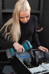 Female IT technician cleaning and repairing server hardware with dust blower in data center
