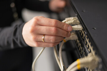 Adult IT technician setting up network cables in a data center and performing maintenance