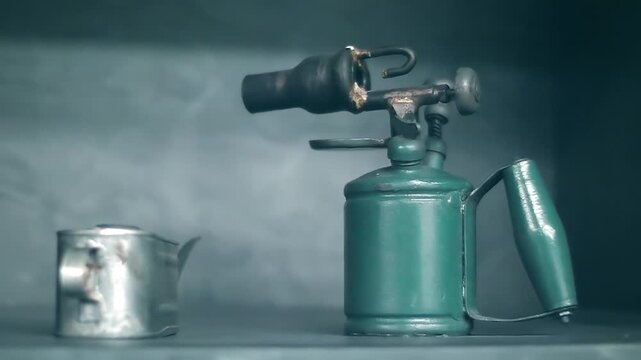 On the shelf there is an obsolete Soviet blowtorch in good condition and a tin oil can. Closeup. Shot in motion  